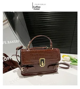 Detail of coffee brown crocodile pattern bag with gold shield clasp and handle