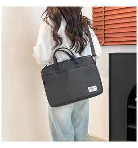 Man carrying a black large capacity laptop bag with adjustable strap in office setting