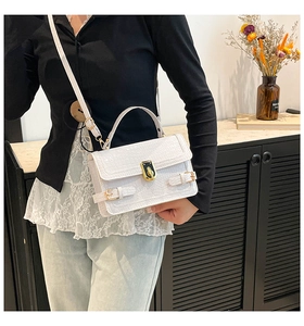 Detail of white crocodile pattern bag featuring golden twist lock and luxury texture