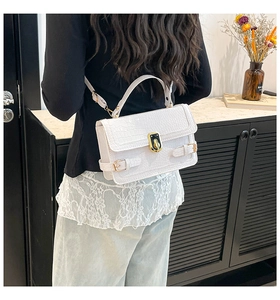 Close-up of white crocodile embossed texture and gold hardware on a crossbody bag