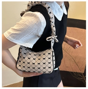 Detail view of plaid underarm bag featuring bow prints and a ruffled shoulder strap