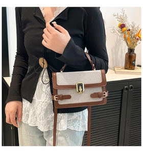 Detail of vintage canvas crossbody bag with dark brown trim and golden metal lock