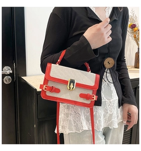 Detail view of red faux leather and beige canvas patchwork crossbody bag with gold clasp