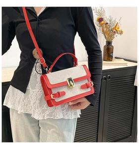 Detail of a red and beige patchwork canvas shoulder bag with gold hardware and PU leather trim