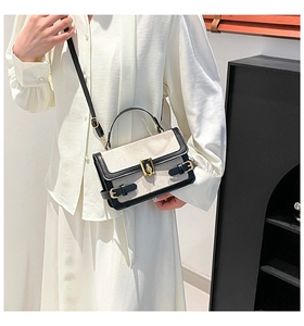 Close-up of contrast stitch canvas handbag with gold twist lock and black leather trim