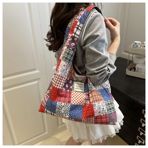 Detailed patchwork canvas tote bag with retro floral patterns and woven labels on shoulder