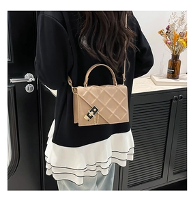 Detail of khaki quilted crossbody bag with gold chain accent and lock closure
