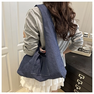 Detail of blue denim tote bag showing the side view with wide shoulder strap and outer pocket
