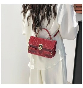 Deep red crocodile texture crossbody bag styled with a white outfit and gold rotary lock