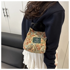 Close-up of a floral jacquard tote bag with nylon handles and a vintage label detail