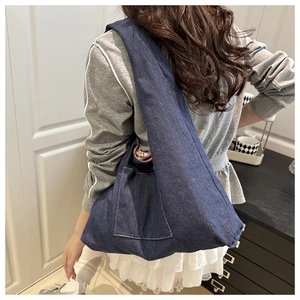 Detail of blue denim hobo bag with white stitching and floral lining on shoulder