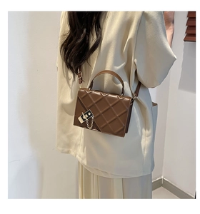 Detailed side view of brown quilted crossbody bag with gold lock and chain strap