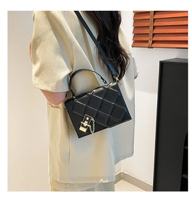 Lifestyle view of a black quilted crossbody bag with gold metal hardware on model