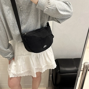 Fashionable black nylon crescent crossbody bag with wide strap worn by a model
