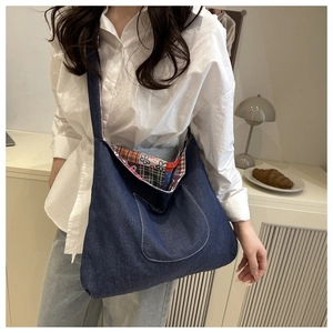 Close-up of denim tote bag showing wide shoulder strap and contrast stitching pocket