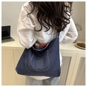 Detail of navy blue denim shoulder bag showing chic contrast stitching and patterned lining