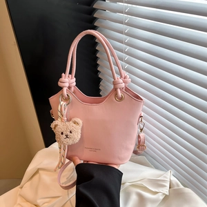 Chic pink bucket handbag with knot handle and plush bear charm for stylish daily commuting