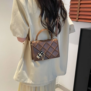 Quilted brown crossbody bag with silver buckle and chain, styled on model for 2025 look