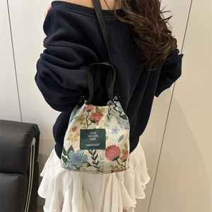 Vintage floral tapestry bucket bag with adjustable straps shown on a female model