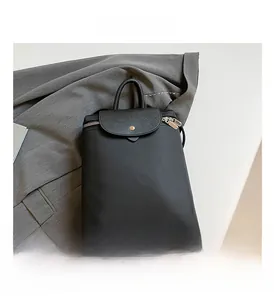 Detail view of black nylon backpack featuring Saffiano leather flap and metal zipper design