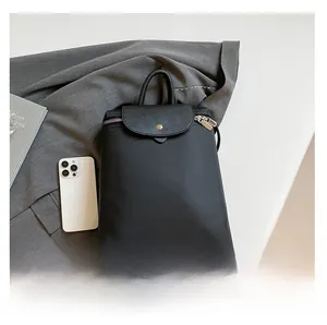 Detail of black backpack showing synthetic fabric texture and golden metal snap buckle