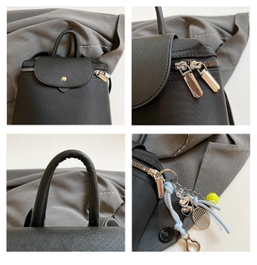 Detail of black cross-grain leather backpack with silver zippers and tennis racket charm