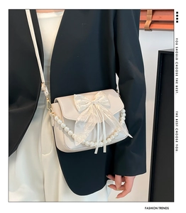 Detail of cream bow shoulder bag with pearl chain and elegant faux leather texture