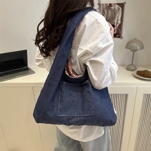 Deep blue denim tote bag with spacious orange patterned lining worn by a model