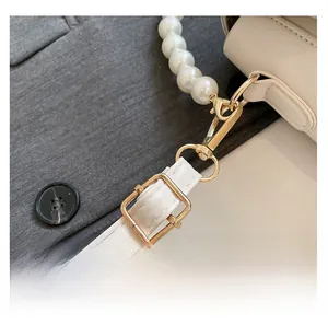 Detail view of the white faux pearl handle and adjustable leather strap with gold hardware
