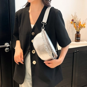 Silver metallic saddle bag with chunky chain and wide strap worn by a model