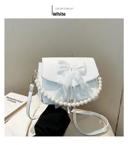 Close-up of white shoulder bag with mesh bow detail and elegant pearl handle strap