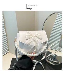 Detail of beige underarm bag featuring a lace bow and elegant pearl chain handle