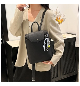 Detail of a chic black backpack being carried by a model in a light blazer