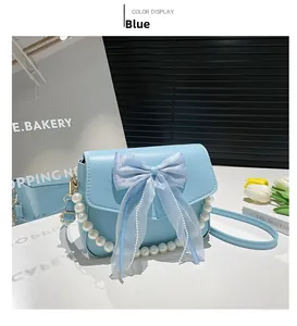Close-up of light blue crossbody bag featuring organza bow and white pearl chain details