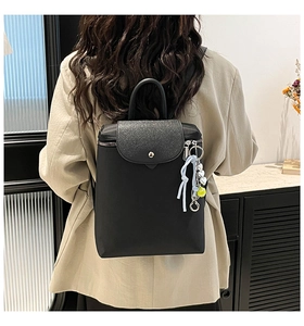 Detail of black backpack with glitter flap, metal button and cute decorative charms