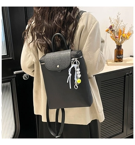 Detail of black backpack with glitter flap, heart pendant, and side zipper in use