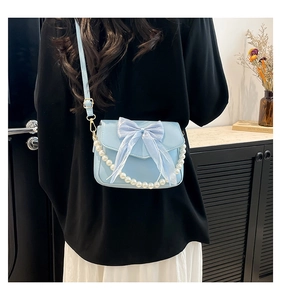 Close-up of light blue underarm bag featuring a tulle bow and pearl chain strap