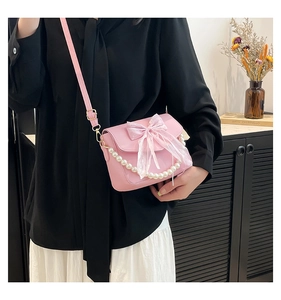 Detailed shot of pink crossbody bag with lace bow and pearl handle chain for women