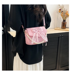 Close-up of pink bow shoulder bag with pearl chain and sleek PU leather texture