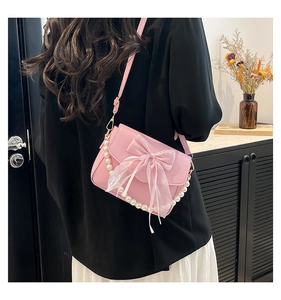 Detail of pink bow handbag with large pearl handle shown on model's shoulder