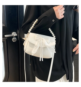 Close-up of white crossbody bag featuring tulle bow detail and elegant pearl handle strap