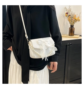 Detailed shot of a white crossbody bag with tulle bow and elegant pearl chain trim