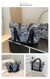 Close-up of zebra stripe travel bag with dual handles and luggage strap on a suitcase