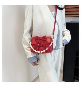 Detail view of a red shoulder bag featuring a tulle bow and elegant pearl handle strap