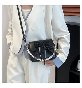 Detail of black underarm bag with large mesh bow and decorative pearl chain strap