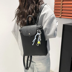 Black minimalist backpack with silver glitter flap and tennis ball charm for travel