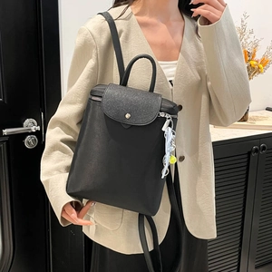 Chic black convertible leather backpack with textured flap and blue charm for women