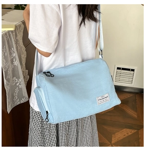 Sac bandoulière en toile bleu clair porté avec sangle réglable et étiquette tissée