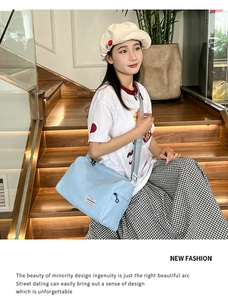 Detail view of light blue messenger bag with adjustable strap and brand tag on stairs