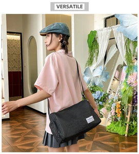 Detail view of a black cylinder crossbody bag with adjustable straps and white woven label